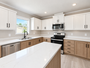 Modern kitchen with white and wood-tone cabinets, white countertops, and stainless steel appliances.